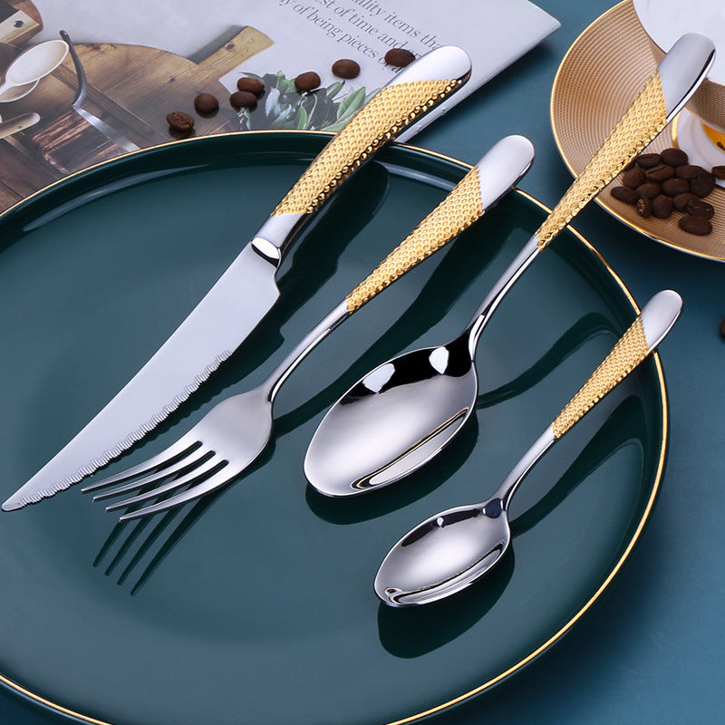 24-piece stainless steel cutlery set with gold accents on a green plate, perfect for elegant dining.
