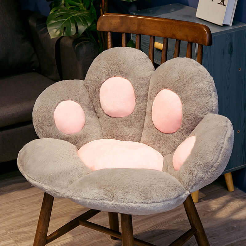 Gray plush cat paw shaped seat cushion for kids' room on wooden chair with pink paw pads, perfect for comfortable seating.